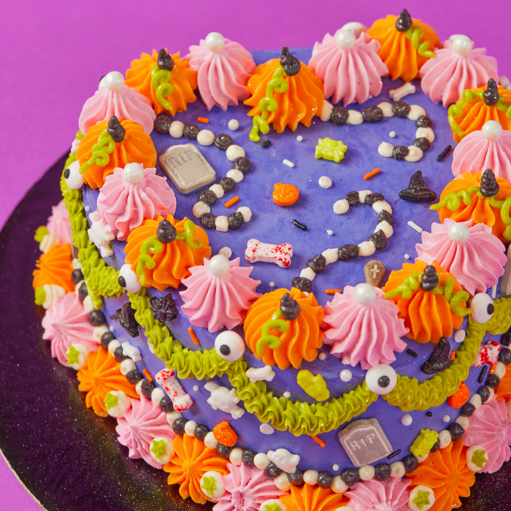 Colorful Halloween-themed cake with purple base on a purple background