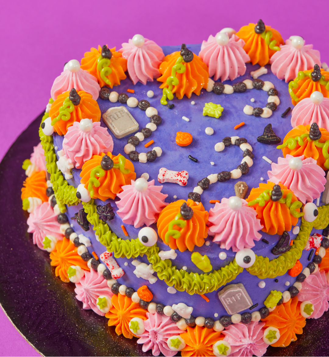 Colorful Halloween-themed cake with purple base on a purple background