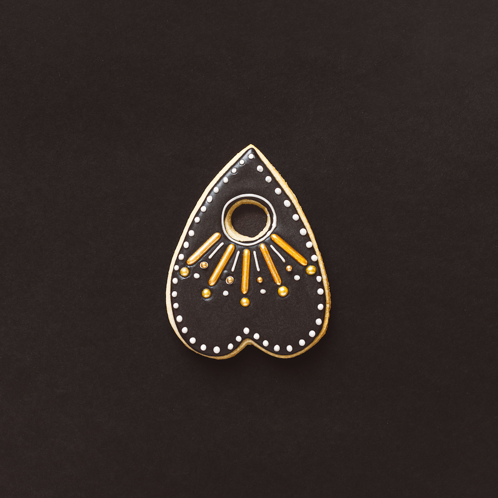 
                  
                    Decorative cookie with gold and white design on a black background
                  
                