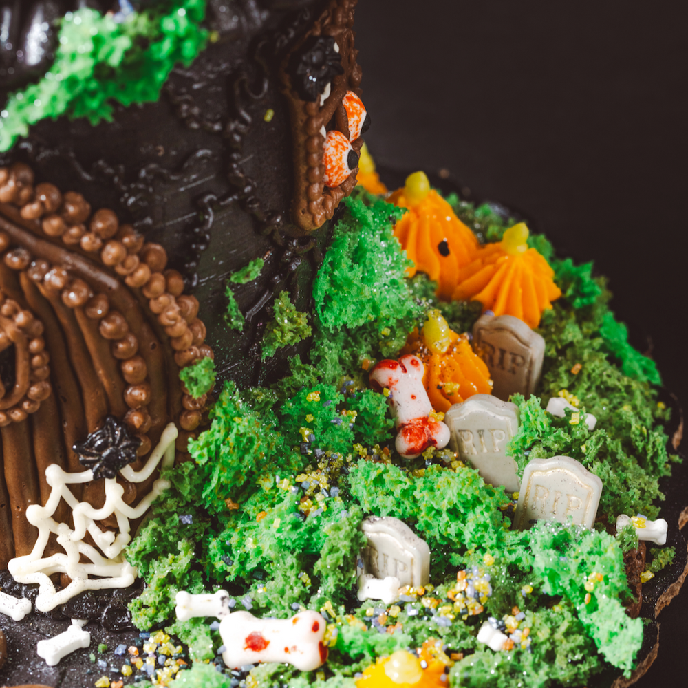
                  
                    Halloween-themed cookie house with decorative elements on a dark background
                  
                